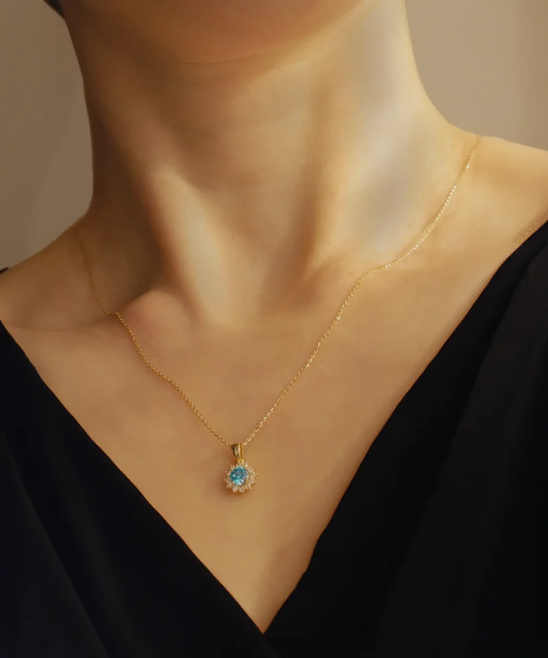 Złota zawieszka z niebieskim kamieniem na szyi