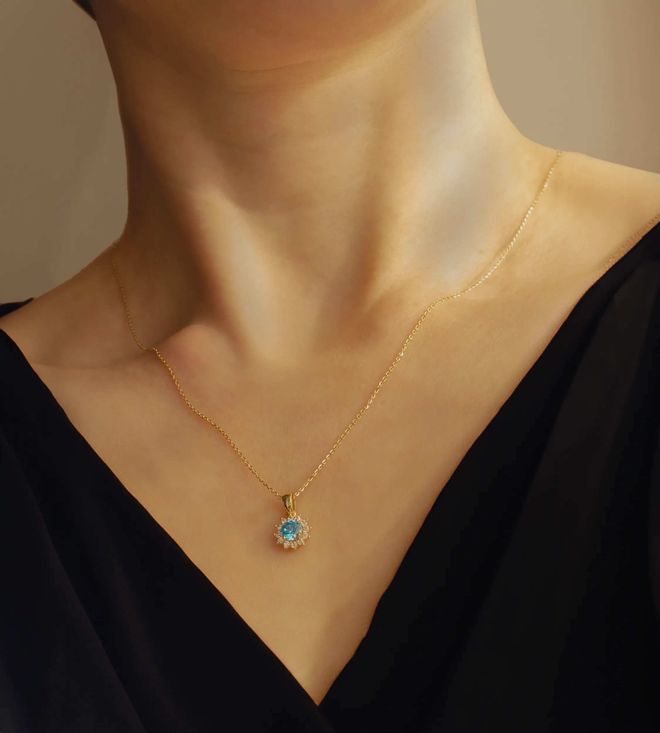 Złota zawieszka z niebieskim kamieniem na szyi