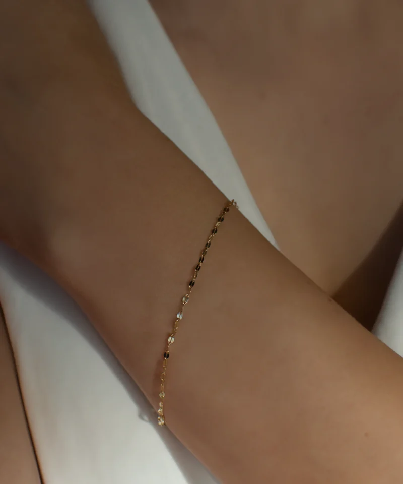 Złota bransoletka z blaszkami w splocie kawa 585 na kobiecym nadgarstku