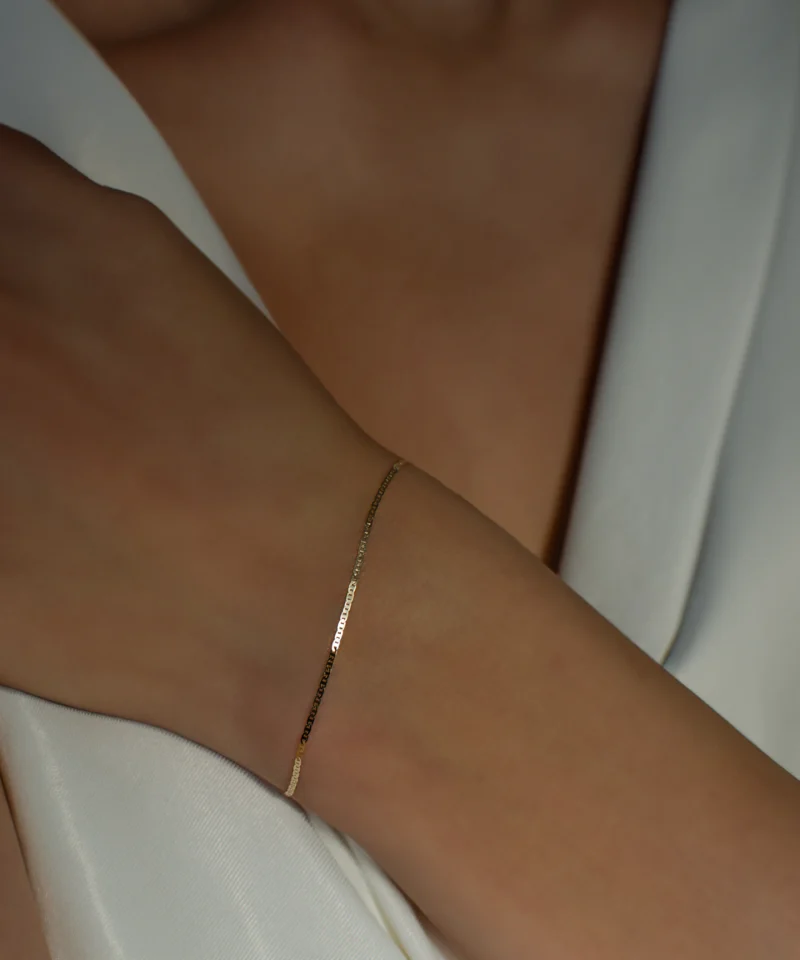 Delikatna złota bransoletka Gucci płaska 585 na kobiecym nadgarstku