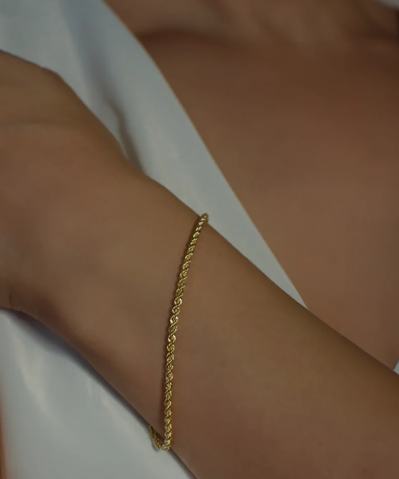 Cienka złota bransoletka kordel 585 na kobiecym nadgarstku