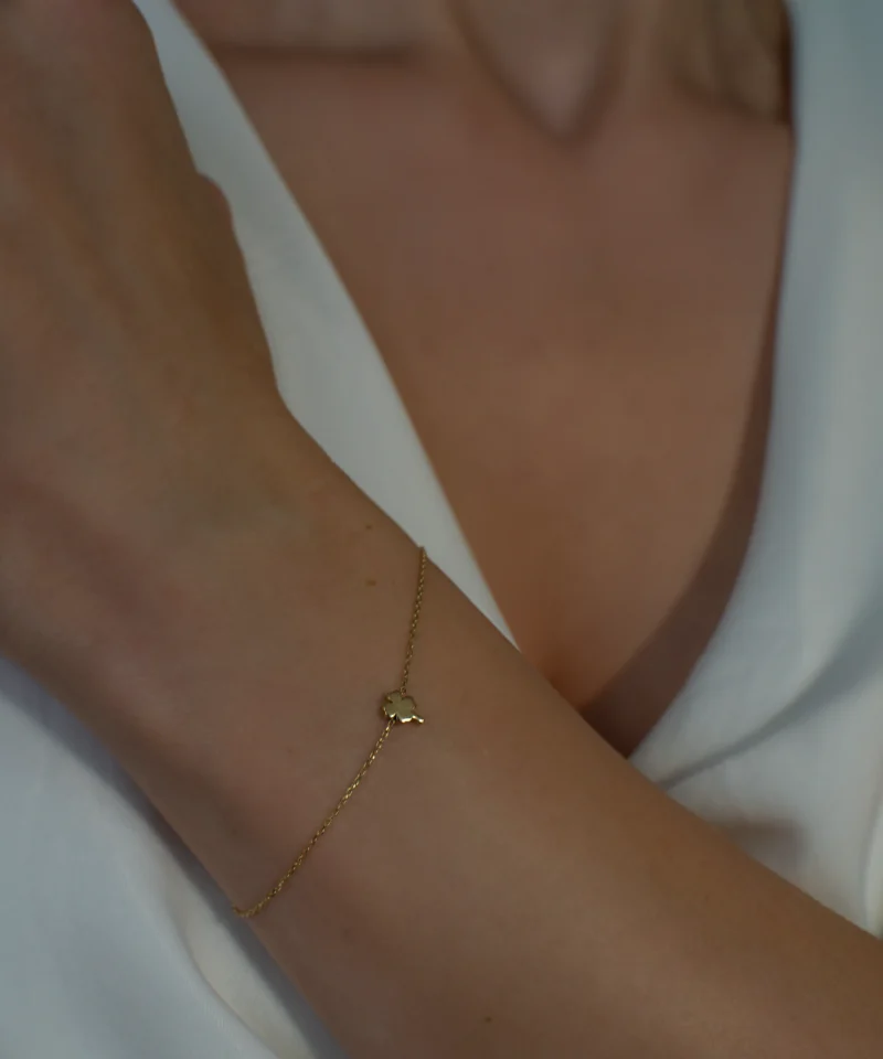 Złota bransoletka z koniczynką czterolistną 585 na kobiecym nadgarstku