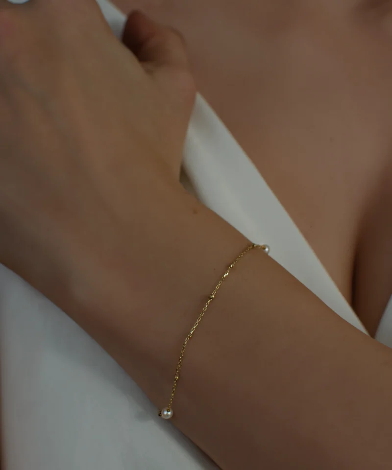 Delikatna złota bransoletka z perłami słodkowodnymi 585 na kobiecym nadgarstku