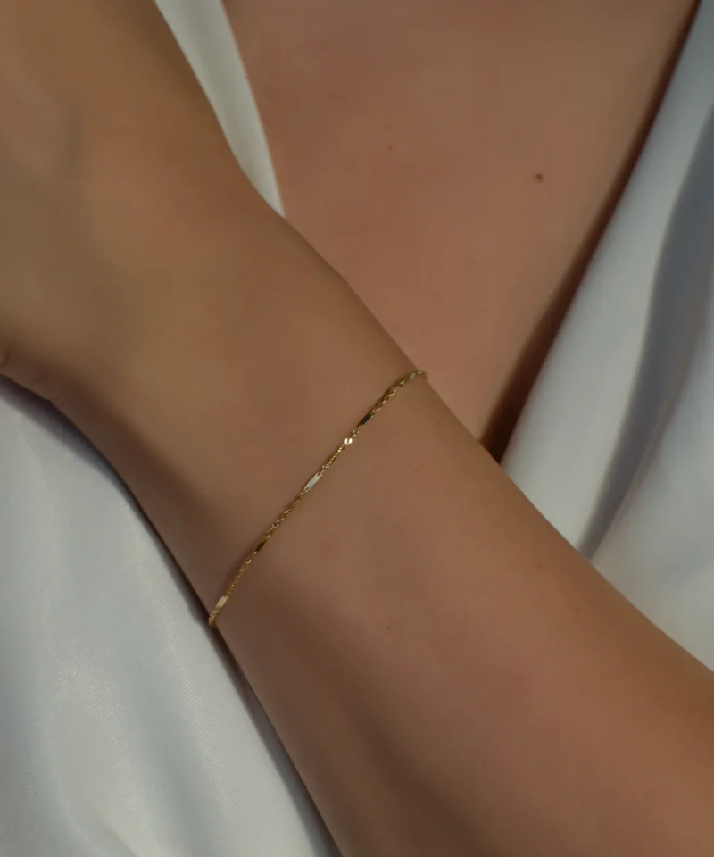Delikatna złota bransoletka singapur 585 z blaszkami na kobiecym nadgarstku