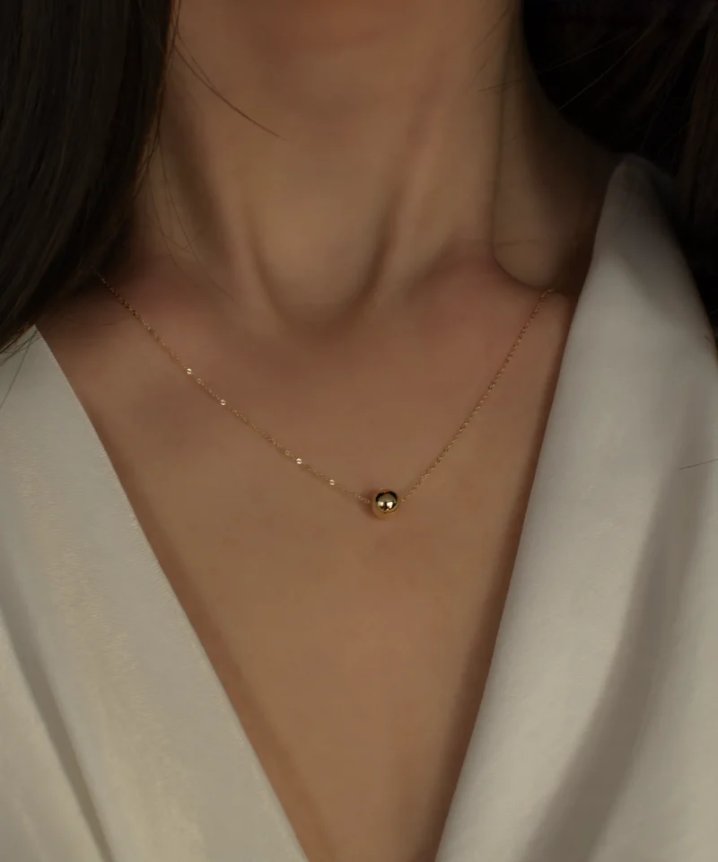 Delikatny złoty naszyjnik ankier z kulką 585 na kobiecej szyi