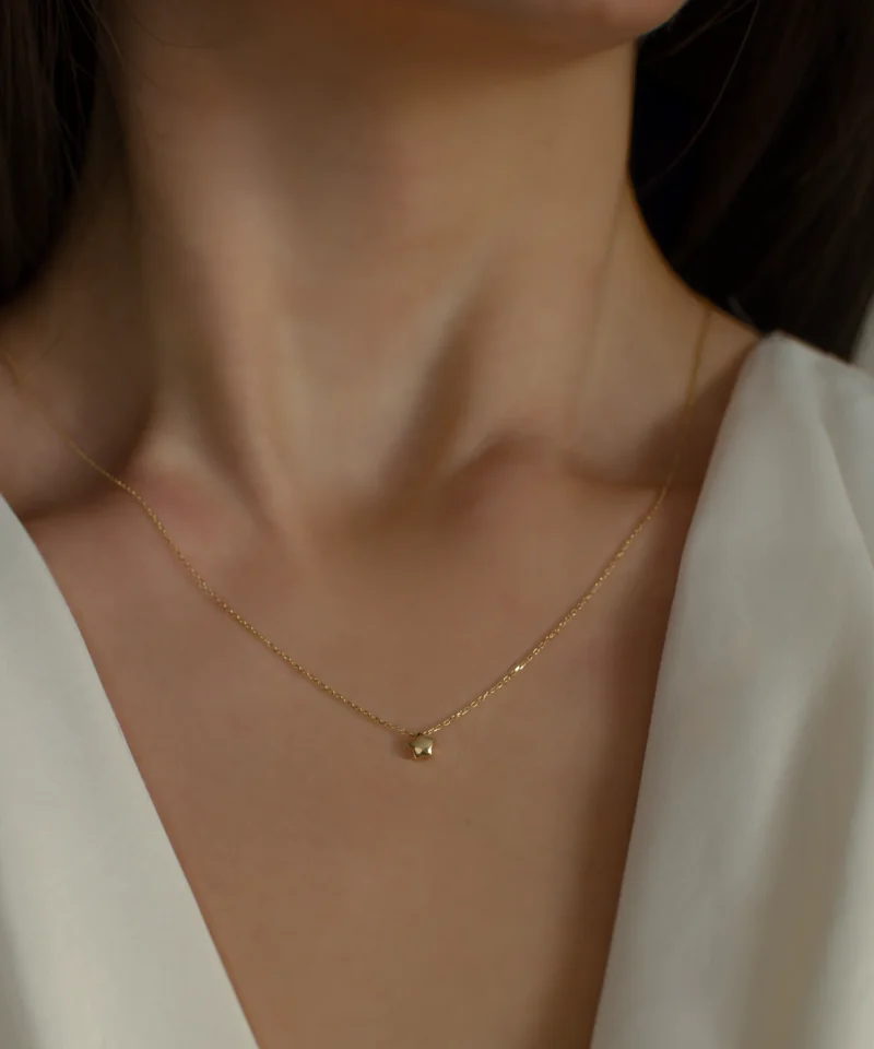 Delikatny złoty naszyjnik ankier z gwiazdką 585 na kobiecej szyi