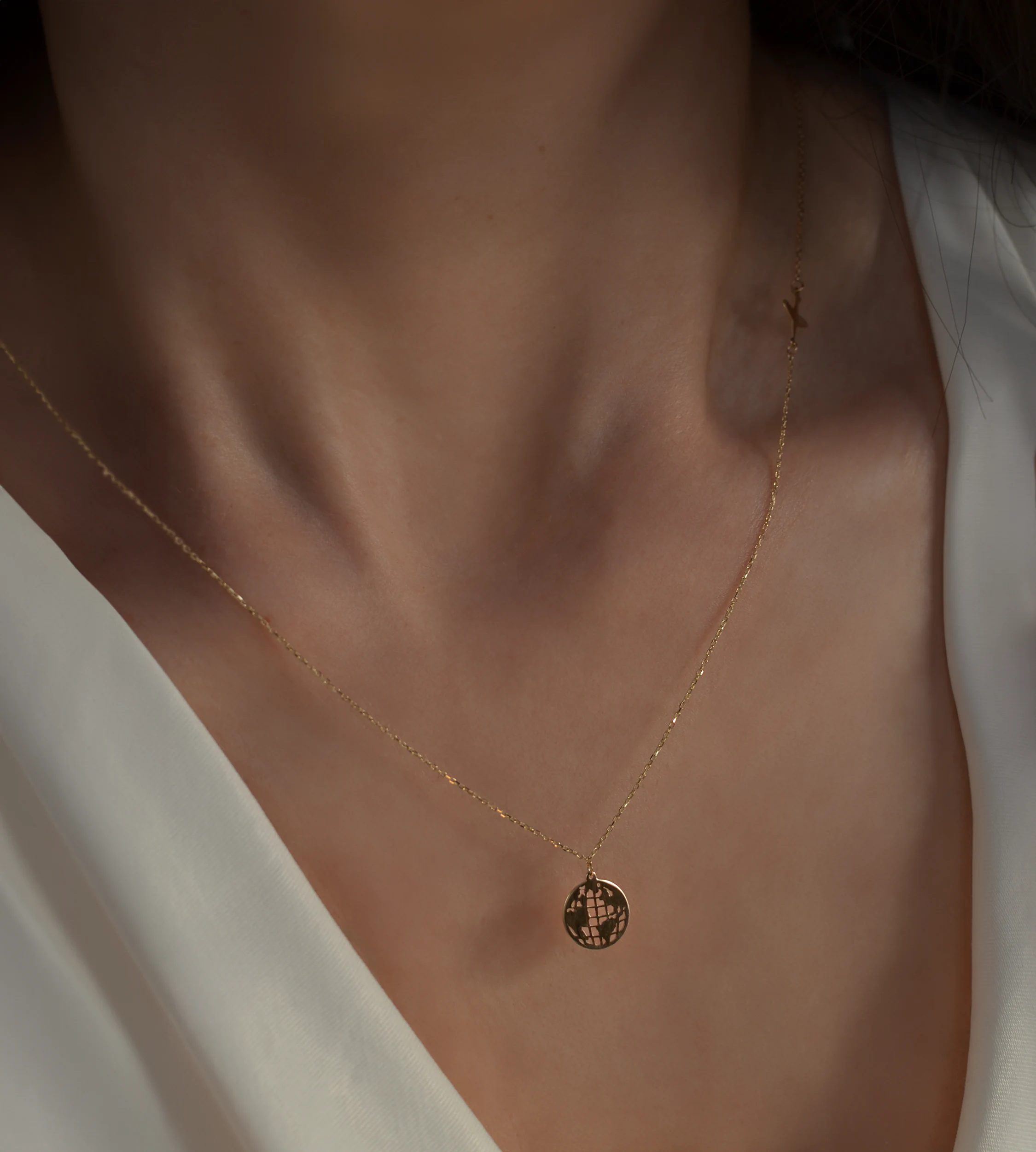 Delikatny złoty naszyjnik ankier z kulą ziemską i samolotem 585 na kobiecej szyi