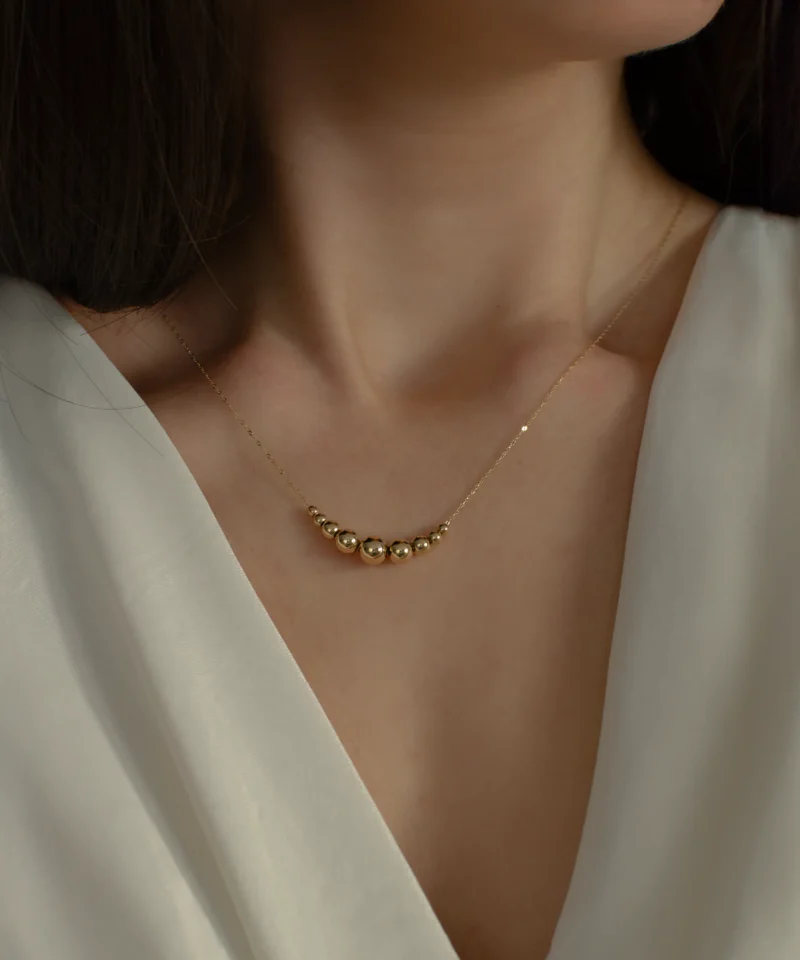 Delikatny złoty naszyjnik ankier z kulkami 585 na kobiecej szyi